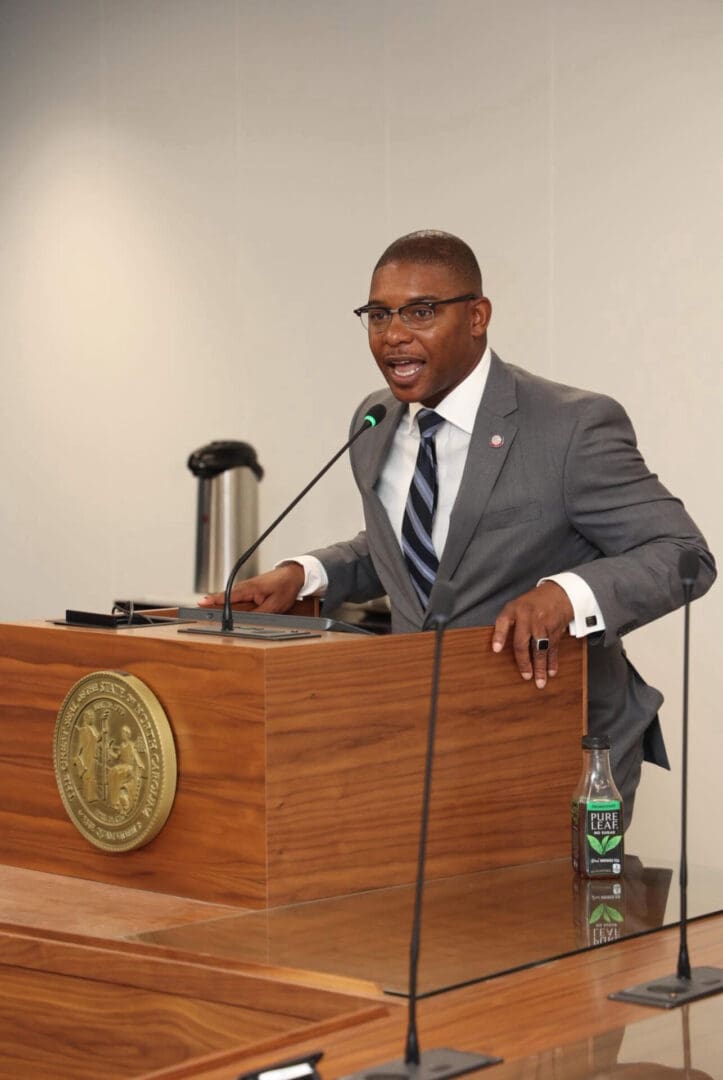 Man in suit speaking at wooden podium